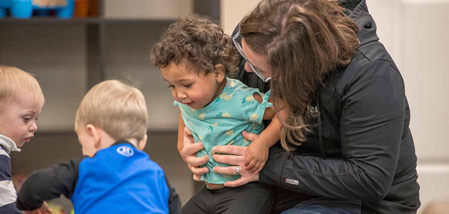 photo of a child care provider on the floor with three toddlers